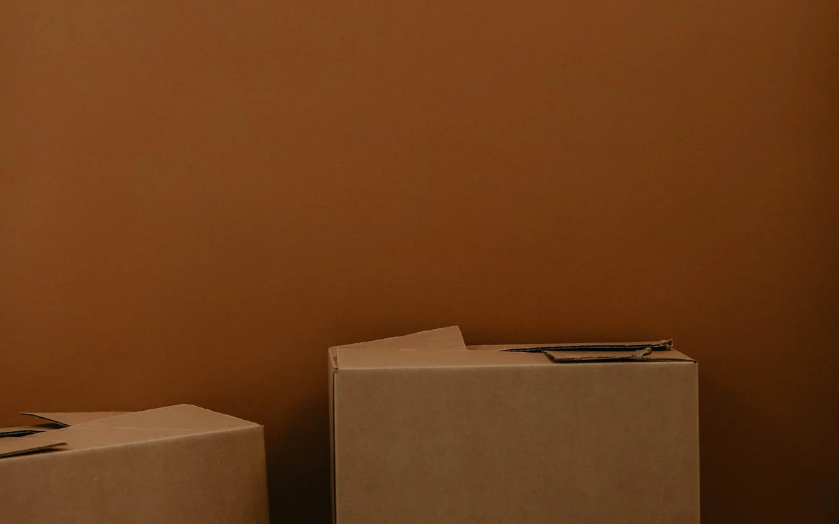Plain cardboard boxes arranged against a warm brown background